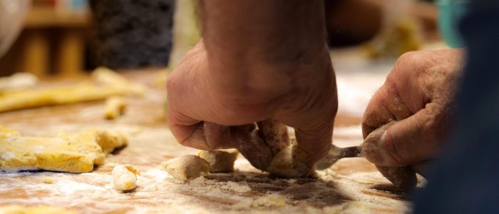 Mani infarinate che impastano e preparano pasta fresca